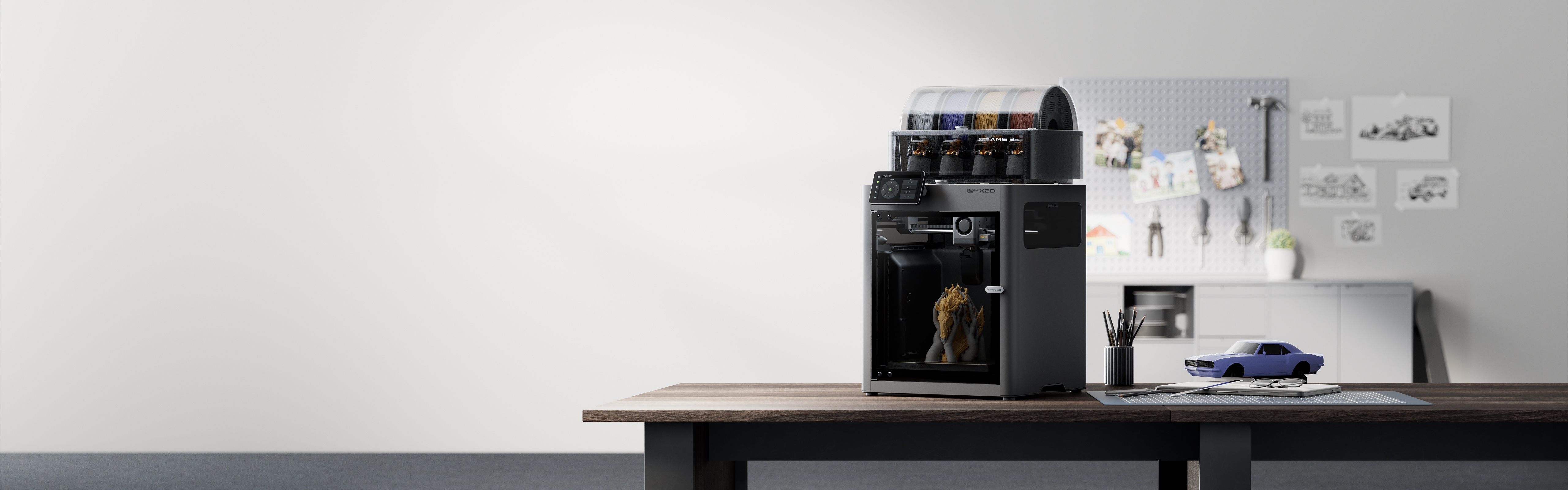 Bambu Lab X2D çift nozullu 3D yazıcı ve yanında basılmış modeller